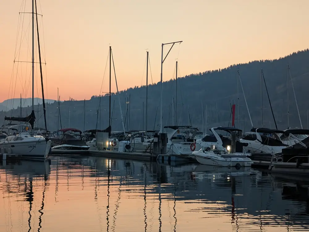 Sailboats and powerboats in the Okanagan Landing marina under a peach sunset sky, September 11, 2025, 7:38 p.m.