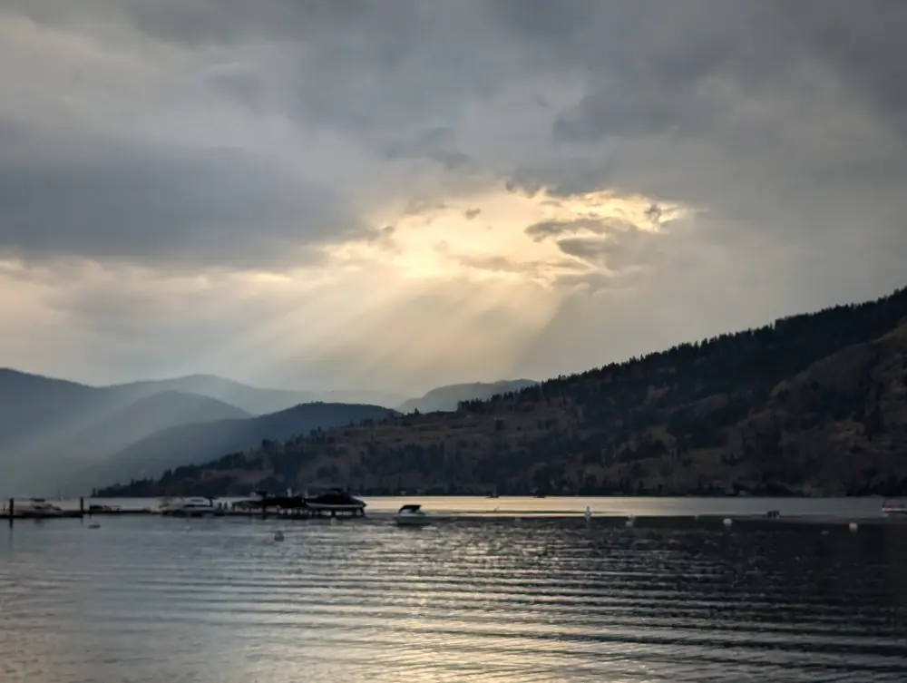 Sun rays breaking through clouds over Okanagan Lake and the hills at Okanagan Landing, August 26, 2024, 6:31 p.m.
