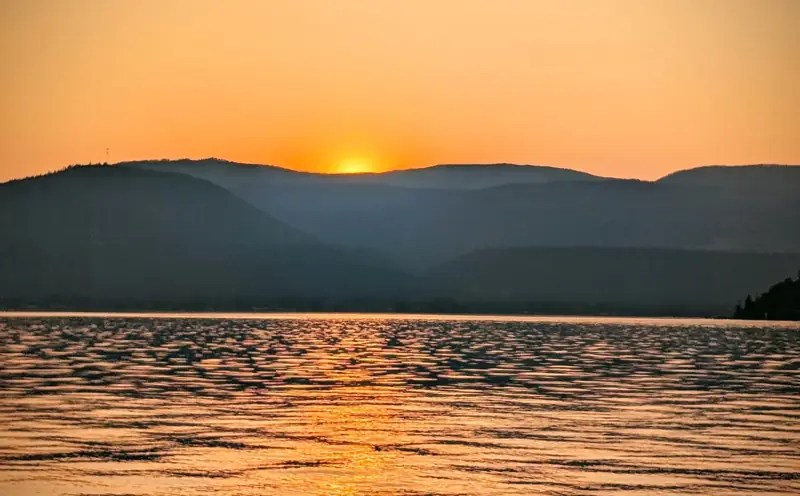 Orange sunset over the hills across Okanagan Lake